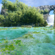 A waterfall leads to a lake in a blue and green screenshot from Sonic Frontiers.